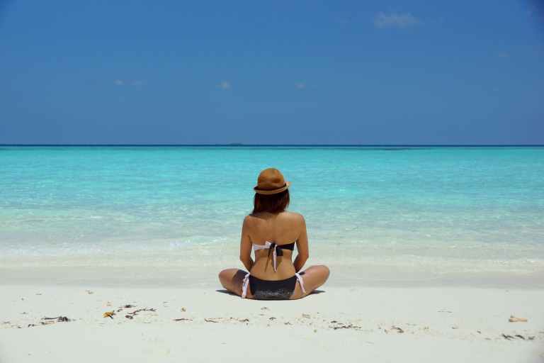 woman wearing black and white brassiere sitting on white sand