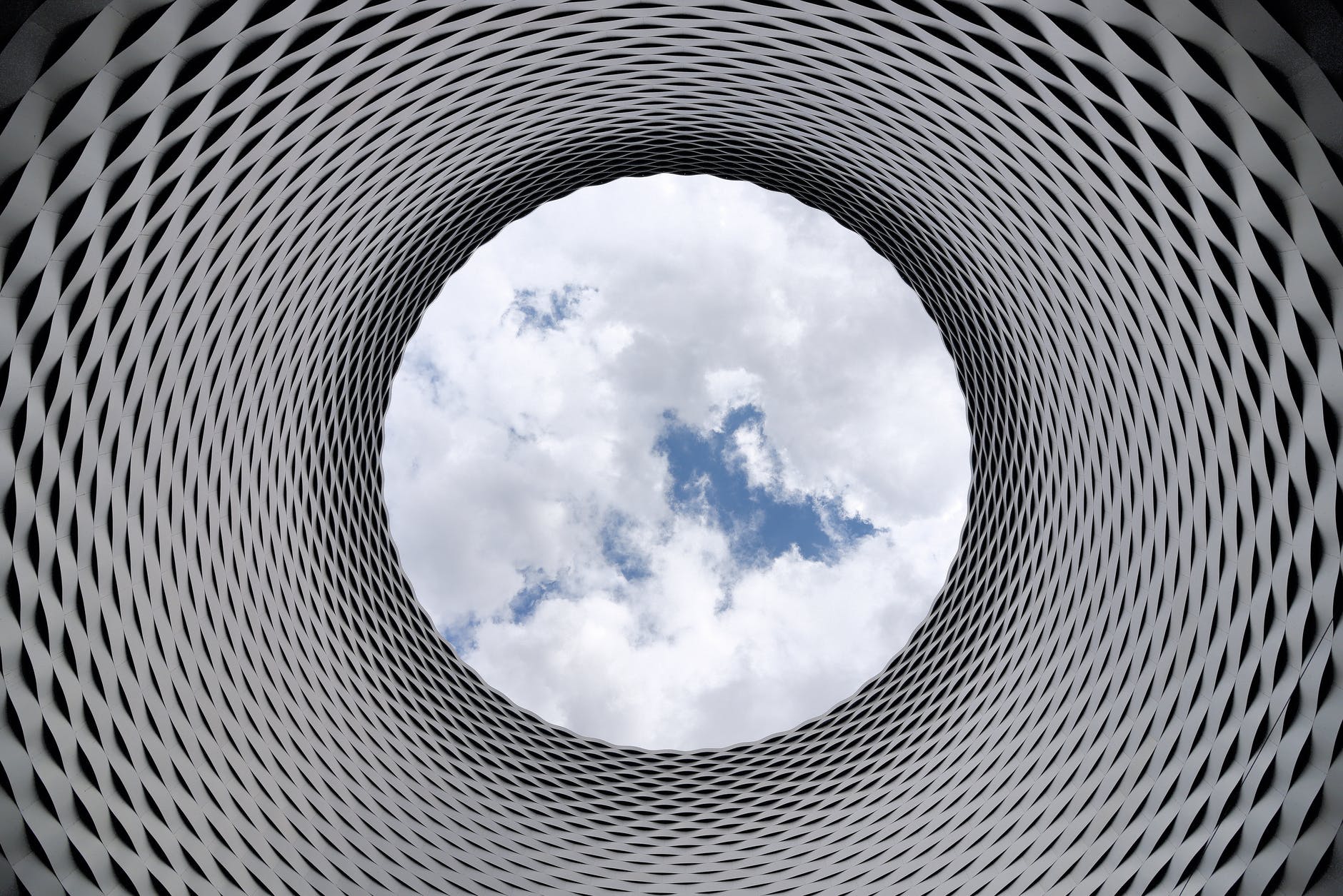 low angle photography of grey and black tunnel overlooking white cloudy and blue sky