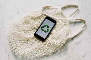 mobile phone with green recycling sign and mesh bag