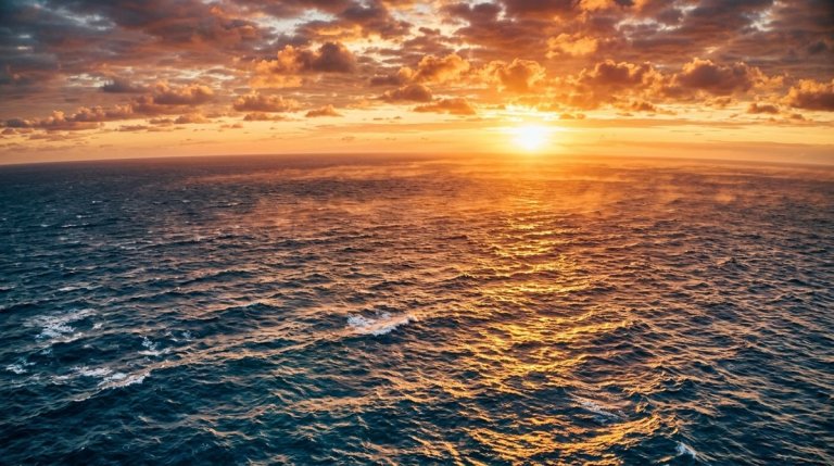 Aerial view of vast open ocean surface glowing with intense sunlight, conveying record heat absorbed by world's oceans in 202