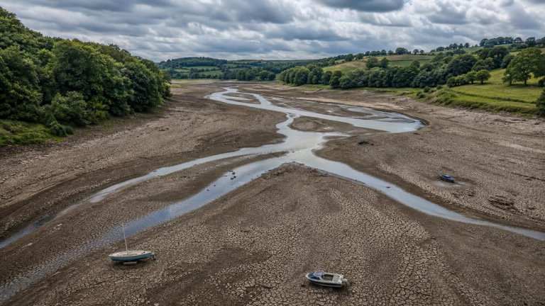 Aerial view of severely depleted Ardingly reservoir with cracked dry earth and stranded boats