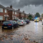 Submerged British residential street during autumn flooding with murky water and heavy rainfall