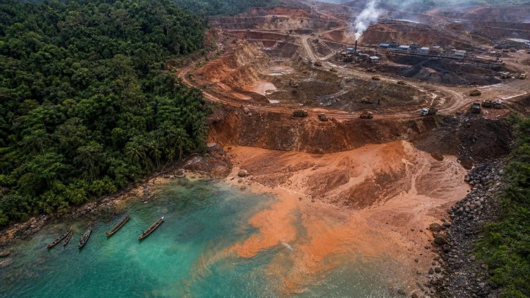 Aerial view of nickel mining operation destroying tropical rainforest with sediment runoff into coastal waters