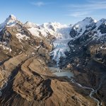 Aerial view of a retreating Swiss glacier exposing bare rocky moraine where ice has melted away in the Alps