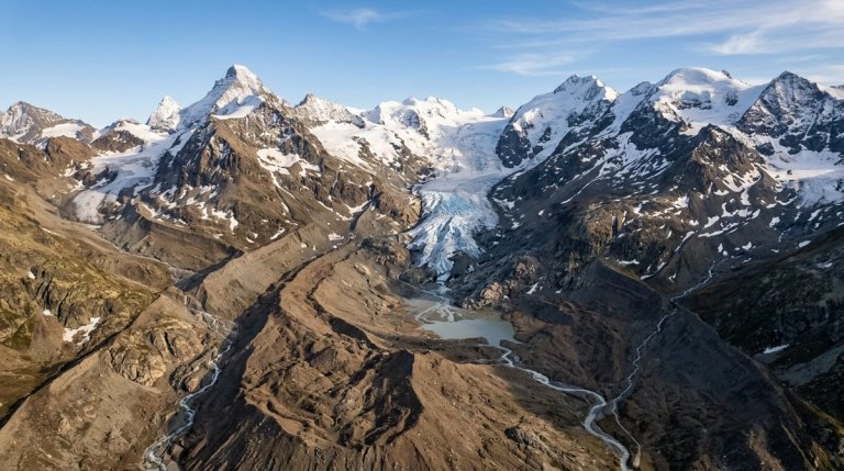 Aerial view of a retreating Swiss glacier exposing bare rocky moraine where ice has melted away in the Alps